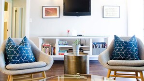 A living room with two armchairs, a coffee table, and a bookshelf. - Boise Guest House (Boise)