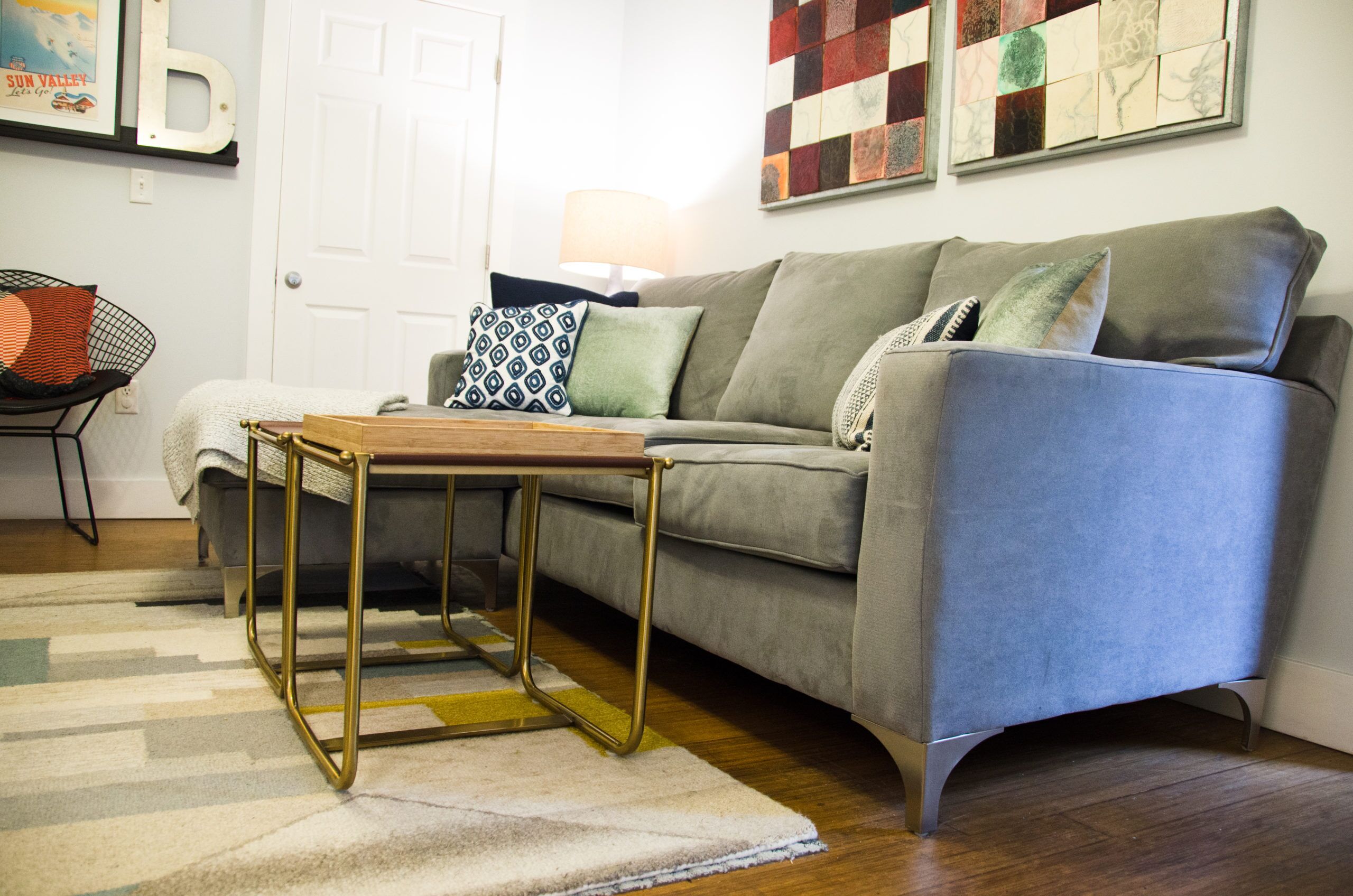 A living room with a grey sofa, a wooden coffee table, and a patterned rug.