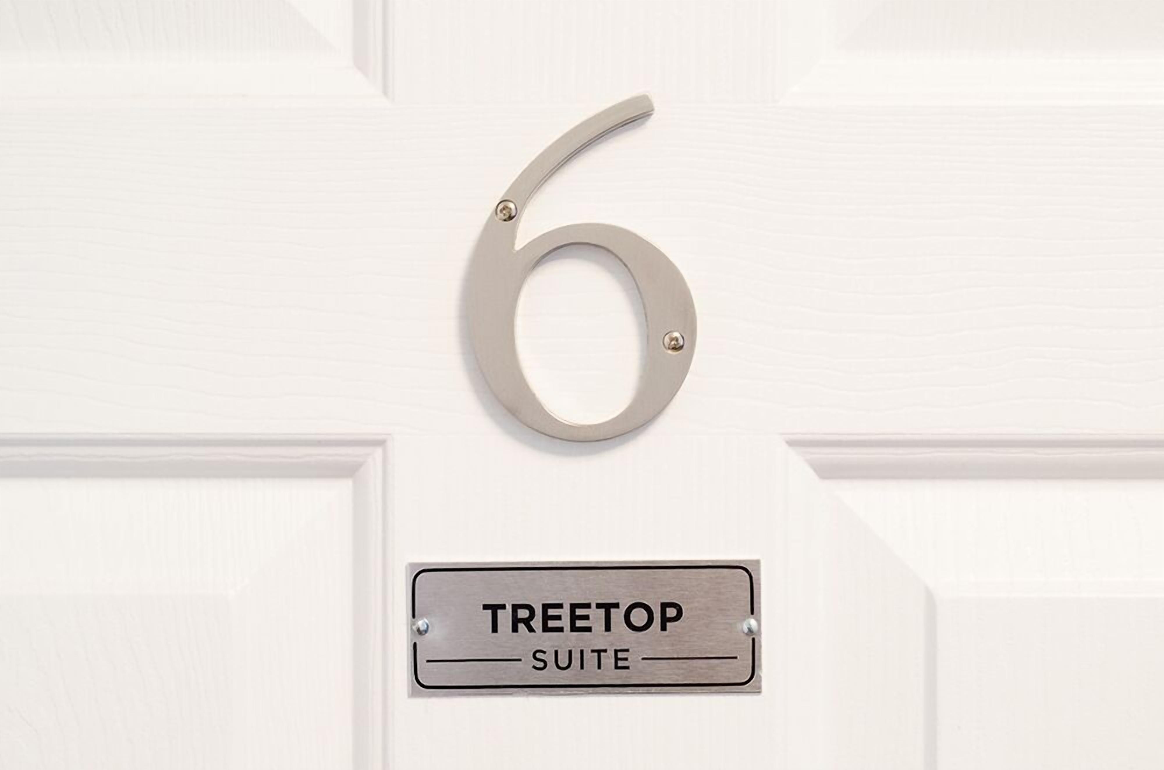 Eine Tür mit der Nummer 6 und einem Schild, das 'TREETOP SUITE' zeigt.