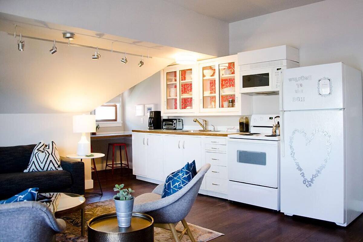 A compact living space with a kitchenette, a dining area, and a seating area with a sofa and chairs.