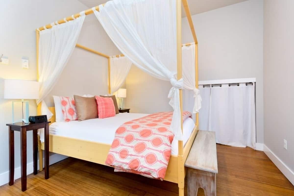 A four-poster bed with a canopy, a bedside table, and a bench.