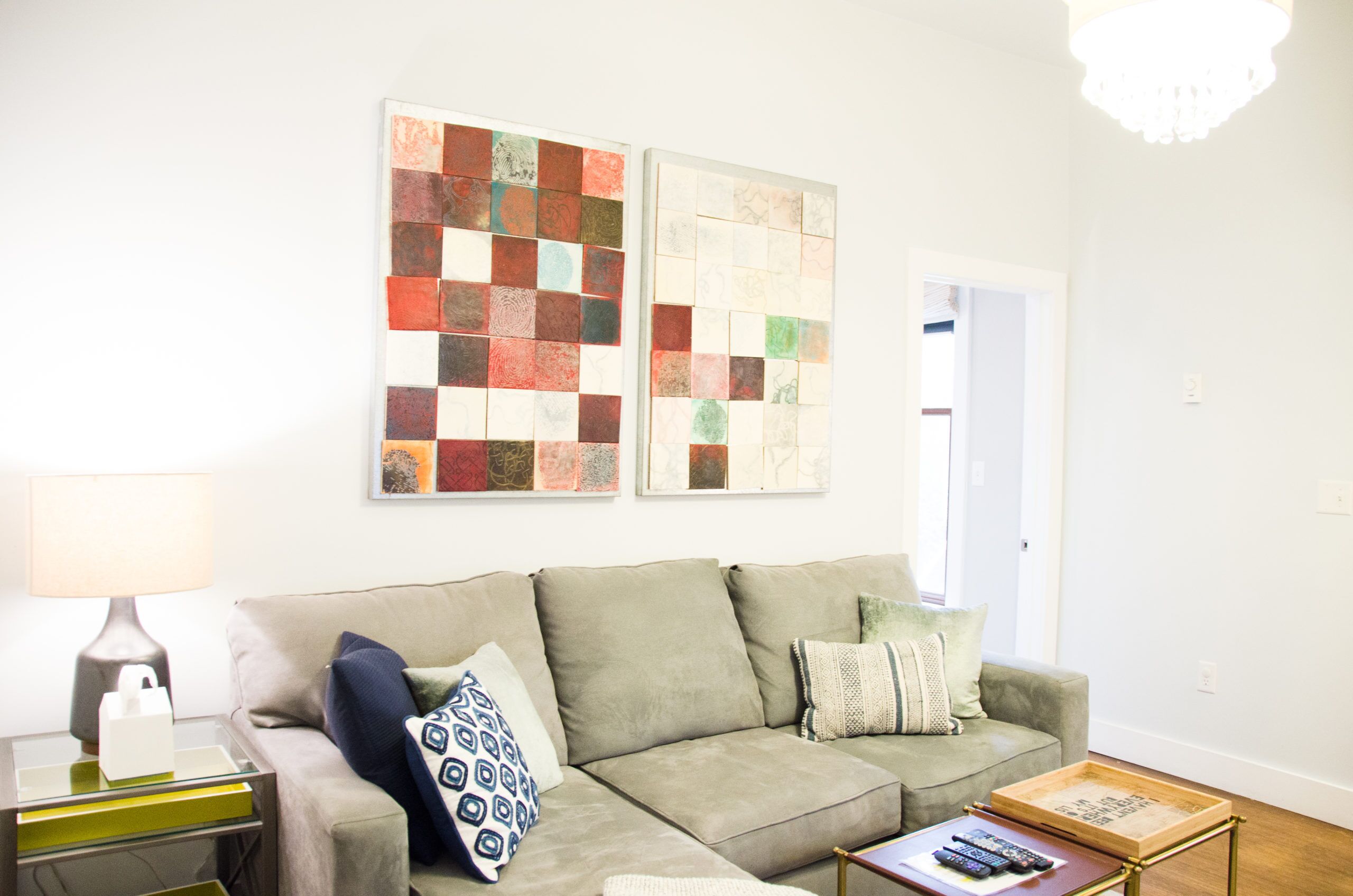 A living room with a sofa, pillows, a coffee table, a lamp, and two wall art pieces.