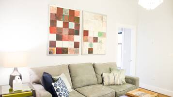A living room with a sofa, pillows, a coffee table, a lamp, and two wall art pieces.