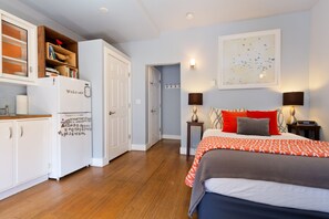Un dormitorio con cama, mesitas de noche, armario y una puerta que da a otra habitación.