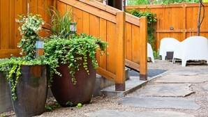 A wooden fence, two large planters with greenery, and a stone pathway. - Boise Guest House (Boise)