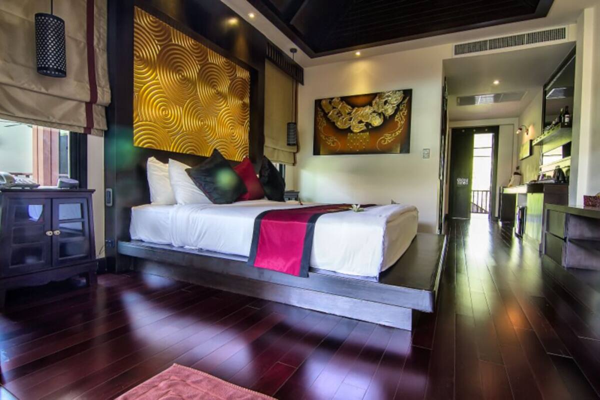 A modern hotel room with a bed, a wooden cabinet, and a dining area.