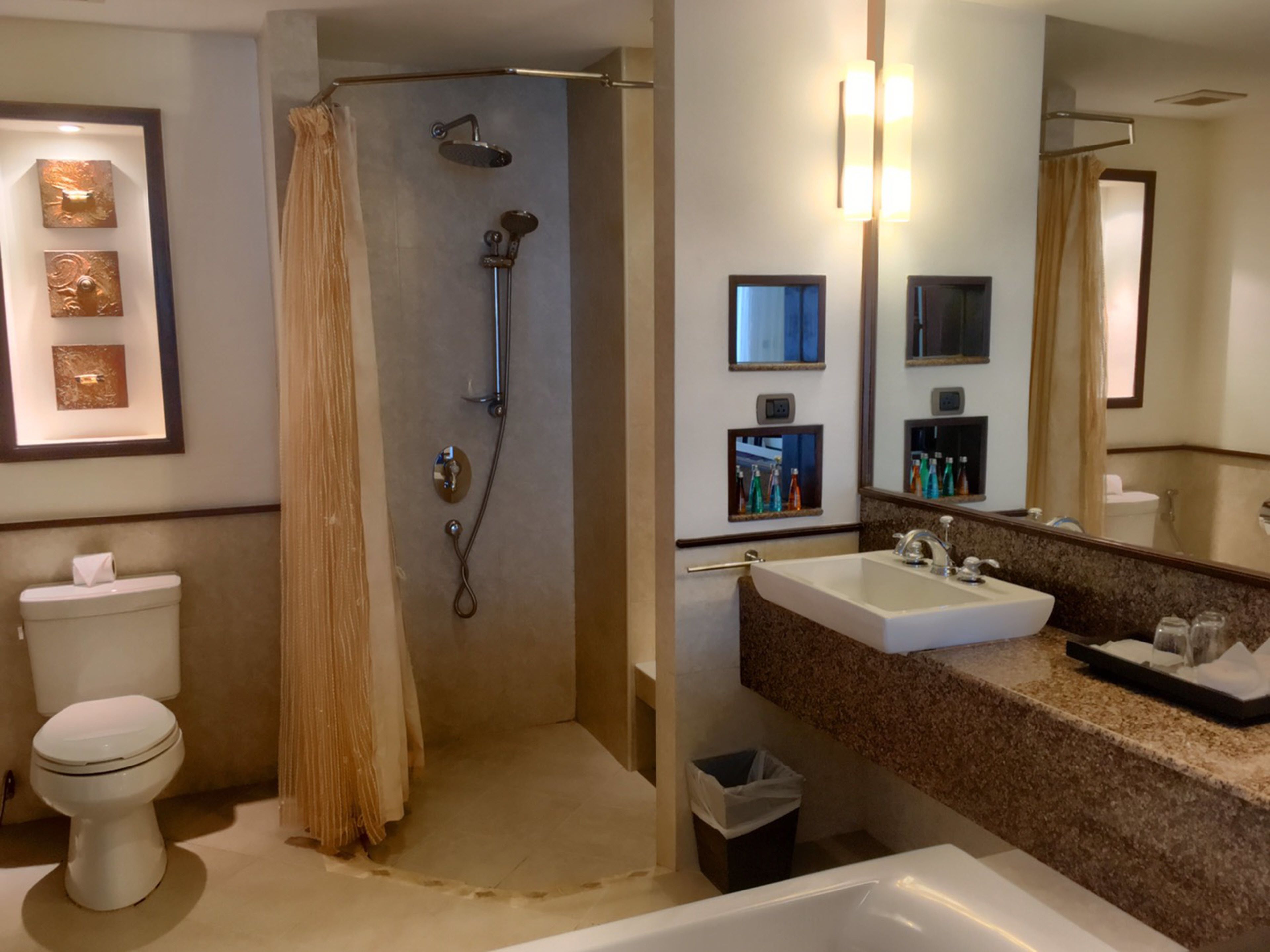 A bathroom with a shower, toilet, sink, and mirrors.
