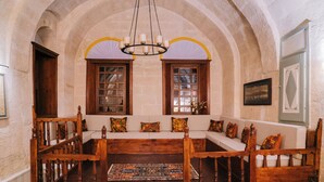 A room with a wooden bench, a chandelier, and arched ceilings.