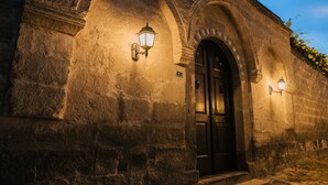 A stone building with arched doorways and two wall-mounted light fixtures.