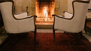 A room with a fireplace, two upholstered chairs, and a patterned rug.