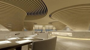 A modern interior with curved ceiling patterns, a dining area with tables and chairs, and a bar area. - Century Palace Hotel (Huizhou)