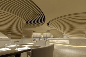 A modern interior with curved ceiling patterns, a dining area with tables and chairs, and a bar area. - Century Palace Hotel (Huizhou)