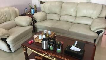 Una sala de estar con un sofá de cuero color beige, una mesa de centro de vidrio con varios objetos y una mesita de noche de madera.