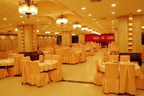 Una sala da banchetto con tavoli rotondi e sedie, una moquette rossa e lampadari.