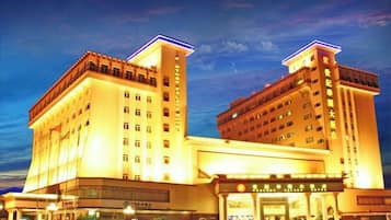 A multi-story hotel with a prominent entrance and a large parking area.