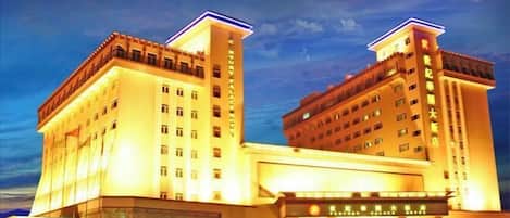 A multi-story hotel with a prominent entrance and a large parking area.