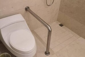 A white toilet with a metal grab bar installed on the wall. - Century Palace Hotel (Huizhou)