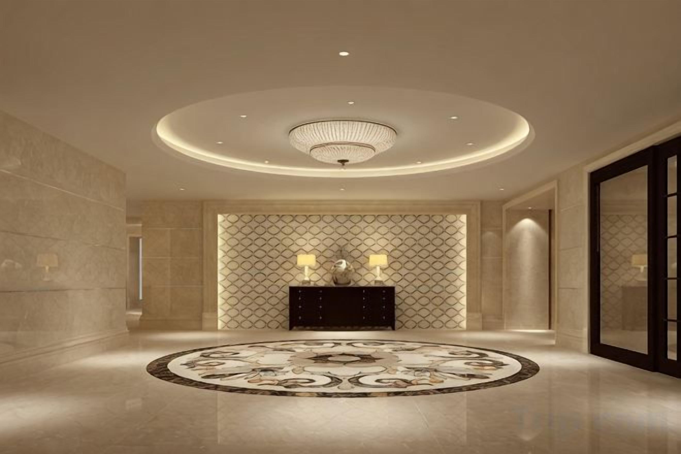 Un hall d’entrée spacieux, agrémenté d’un grand tapis rond au centre, d’un mur décoratif aux motifs géométriques et d’un luminaire au plafond.