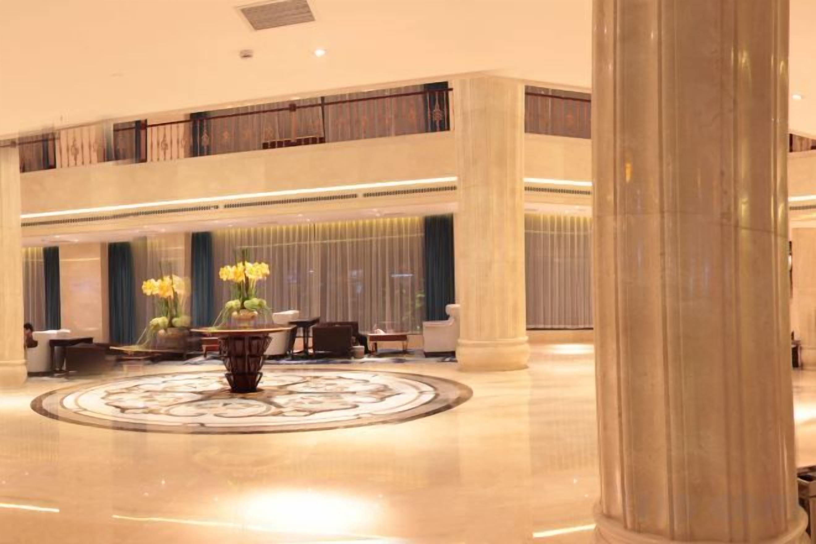 Eine geräumige Lobby mit einer zentralen Zierbrunnen, Sitzbereichen und einer hohen Decke mit einem Balkon.
