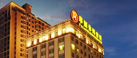 Un edificio de hotel de varios pisos con señalización iluminada y un logotipo circular destacado en la fachada.