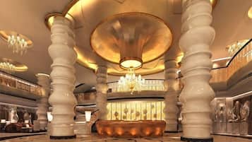 A grand lobby with large columns, a central seating area, and chandeliers.