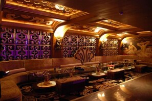 A luxurious lounge with ornate wall panels, plush seating, and a bar area. - Century Palace Hotel (Huizhou)