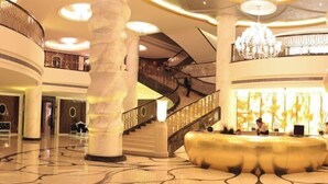 A spacious lobby with a grand staircase, marble columns, and a chandelier. - Century Palace Hotel (Huizhou)