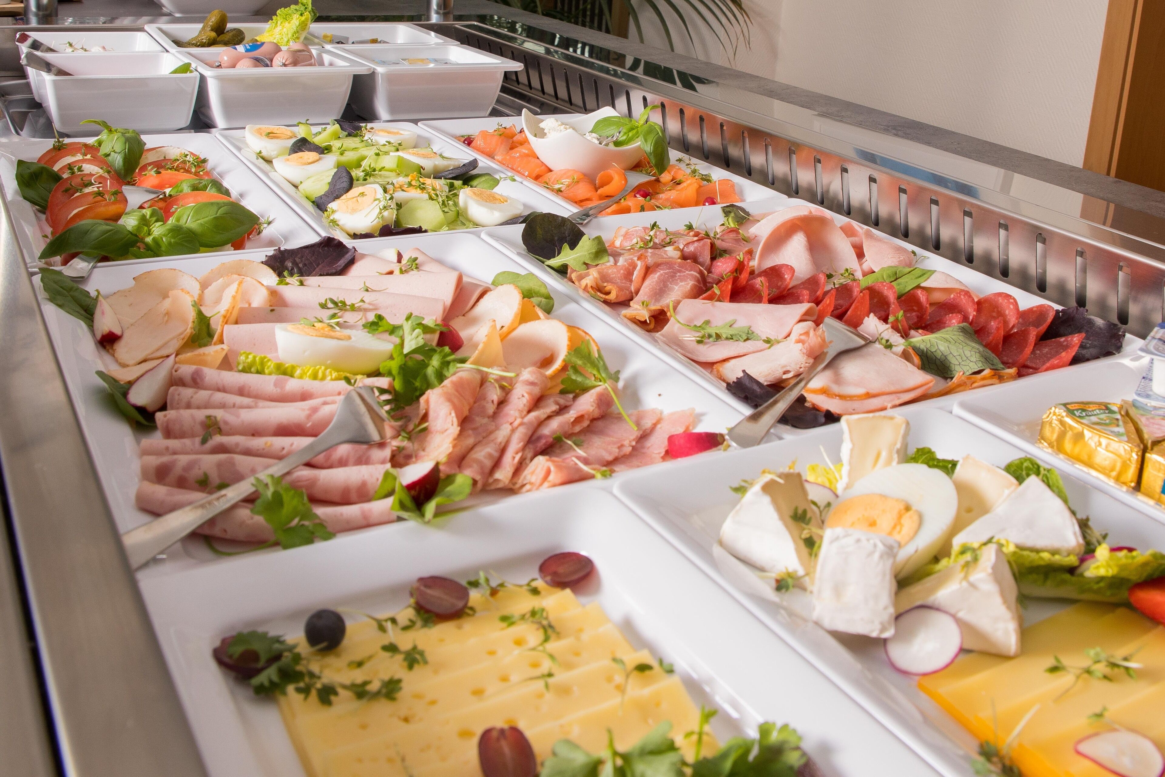 A buffet with various food options including meats, cheeses, and salads.