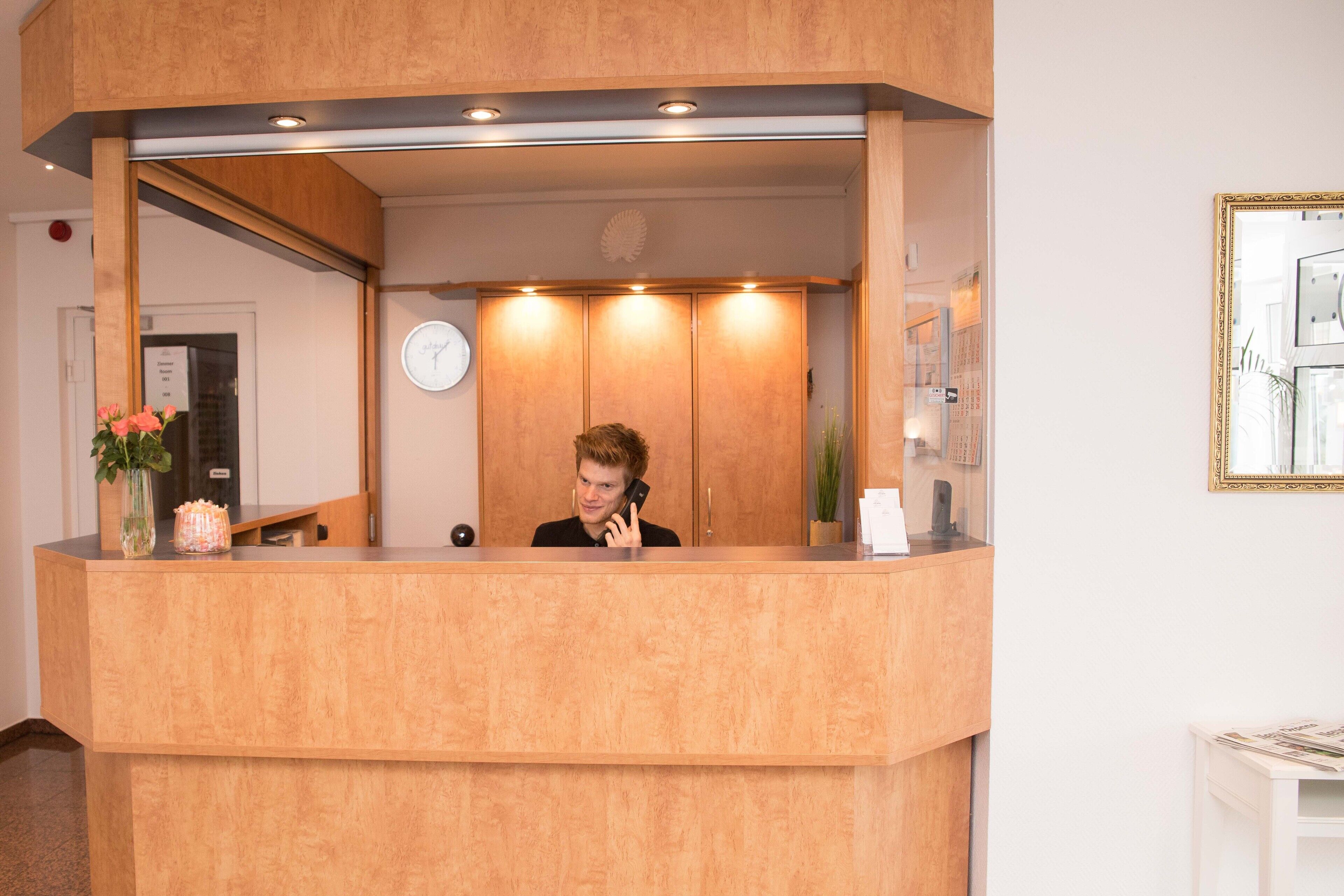 A wooden reception desk with a clock on the wall behind it.