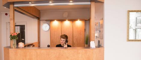 A wooden reception desk with a clock on the wall behind it.