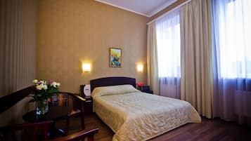 Une chambre d’hôtel avec un lit, un bureau et une chaise, un vase avec des fleurs et un tableau au mur.