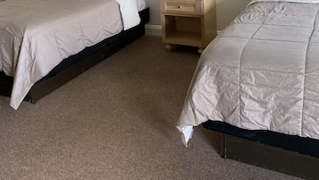 Ett hotellrum med två sängar, ett nattduksbord med en lampa och ett rum med heltäckningsmatta.