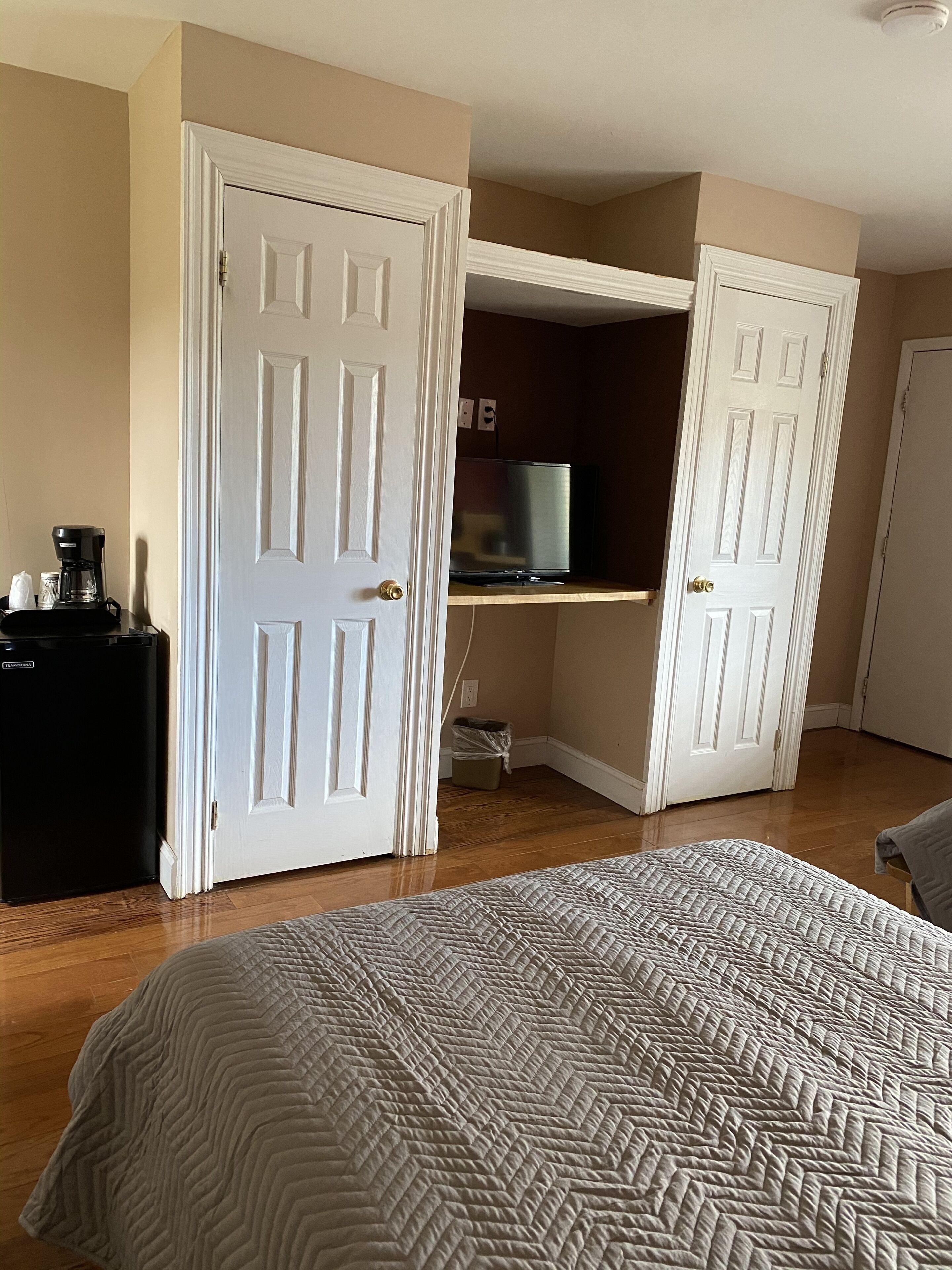A hotel room with a bed, a desk with a computer, and a coffee maker.