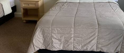 A hotel room with a large bed, a nightstand with a lamp, and a wooden headboard.