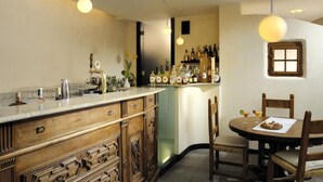 A kitchen with a bar area, wooden cabinets, and hanging pendant lights. - Miramonti Park Hotel (Bormio)