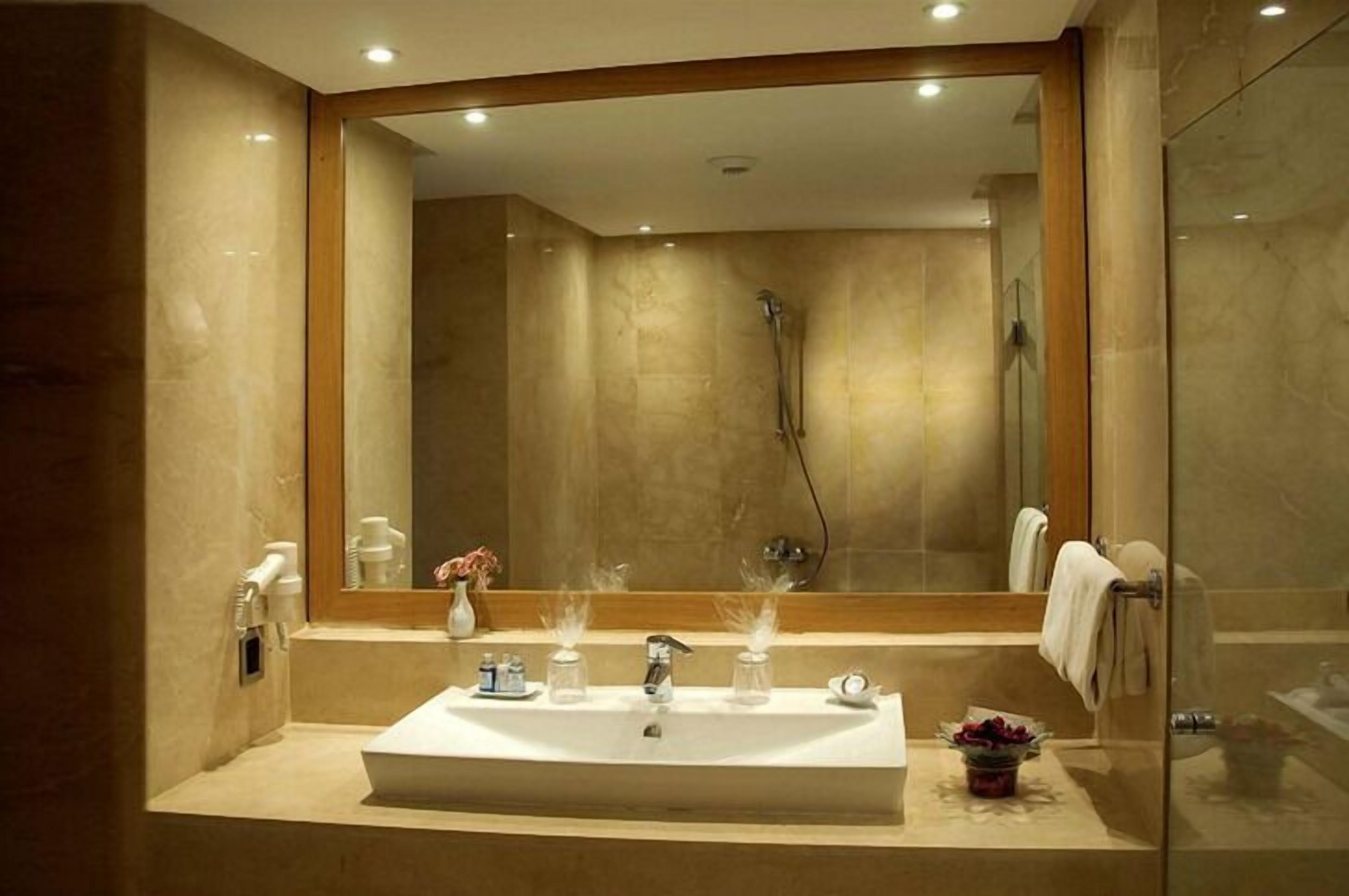 Une salle de bain moderne avec un grand miroir, un lavabo rectangulaire et une douche à parois en verre.