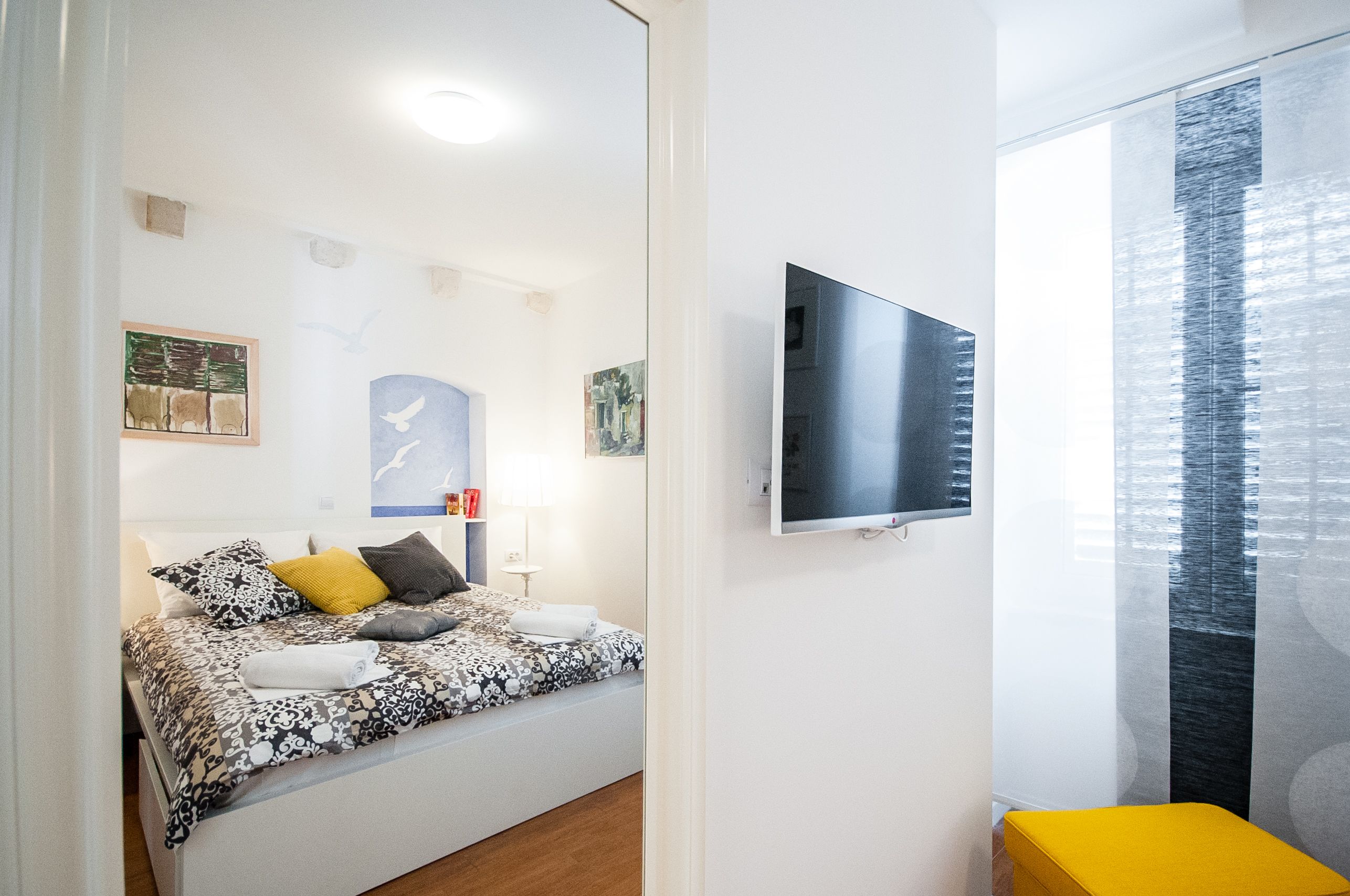 Een moderne slaapkamer met een bed, een televisie en kunstwerken aan de muur.