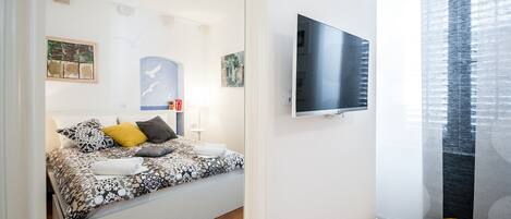 A modern bedroom with a bed, a TV, and artwork on the walls.