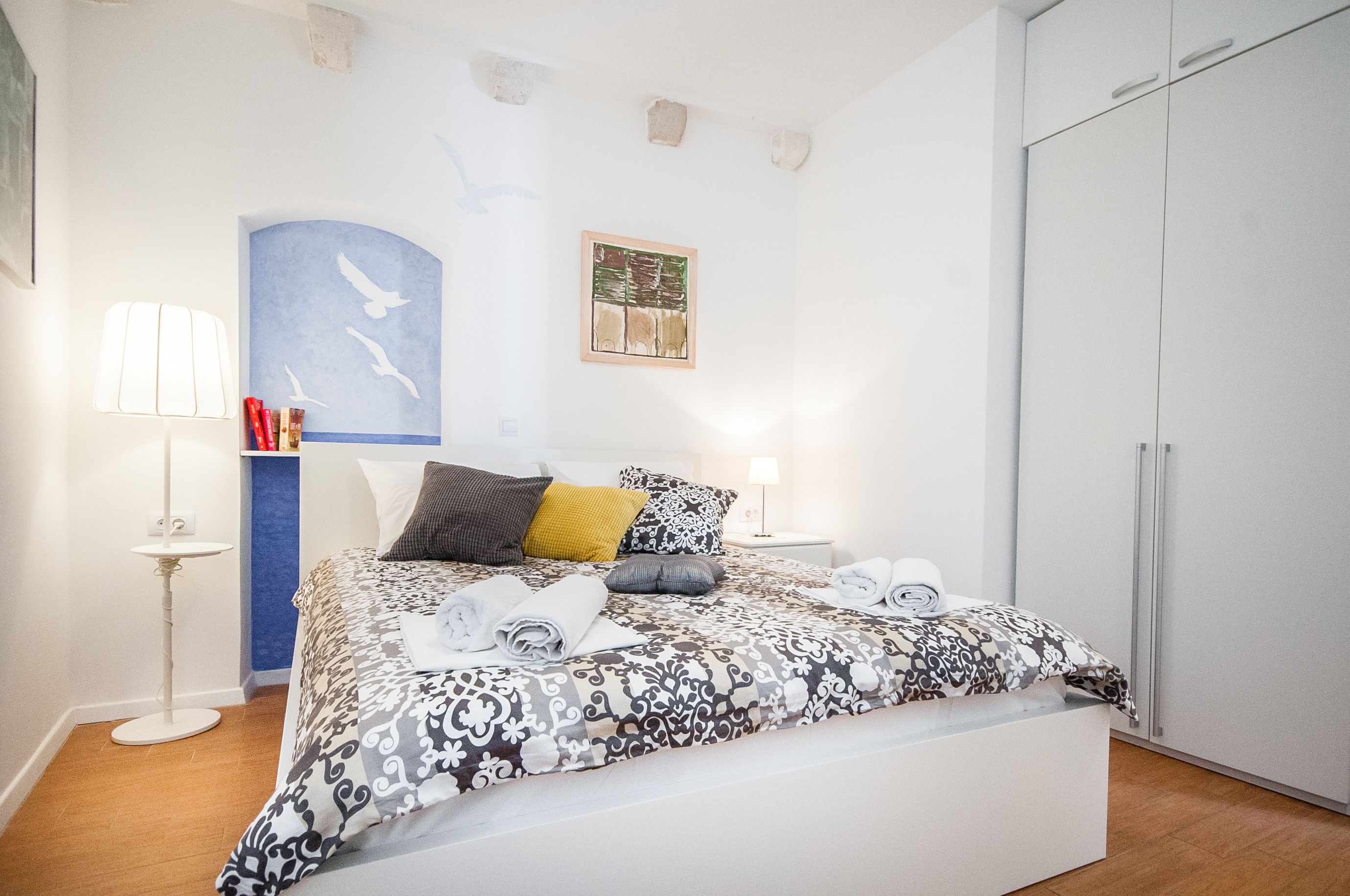 Une chambre à coucher avec un lit, des tables de chevet, une armoire et des œuvres d’art accrochées au mur.