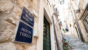 Una calle estrecha con un letrero que dice "APARTMAN HOUSE TEREZA" y una escalera que conduce a un edificio.