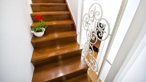 Una escalera de madera con barandilla blanca y una maceta con flores rojas.