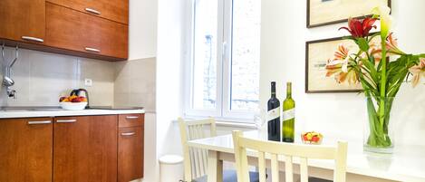 Una cocina con armarios de madera, una mesa de comedor con sillas, un jarrón con flores y una ventana con vistas.
