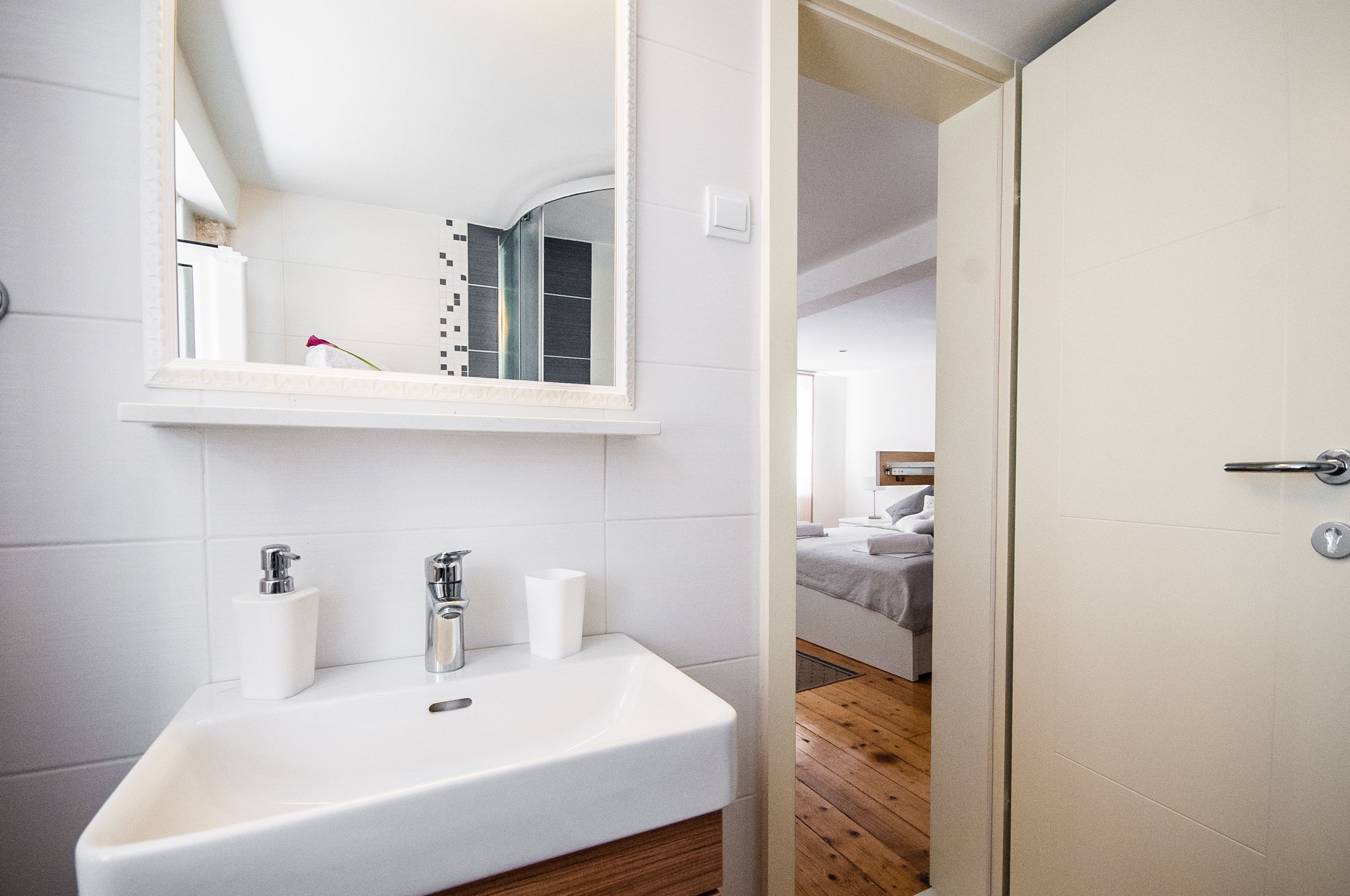A modern bathroom with a white sink, two faucets, and a mirror.