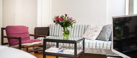 A living room with a sofa, armchair, coffee table, and a TV.
