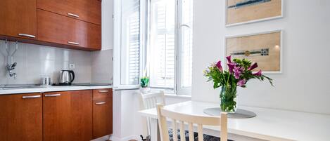 Eine moderne Küche mit Holzschränken, einer weißen Arbeitsplatte und einem Essbereich mit weißem Tisch und Stühlen.