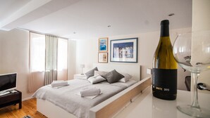 Una habitación de hotel moderna con una cama, un televisor, una botella de vino y una copa de vino.