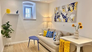 Una sala de estar moderna con un sofá, una mesita, una lámpara y un cuadro en la pared.