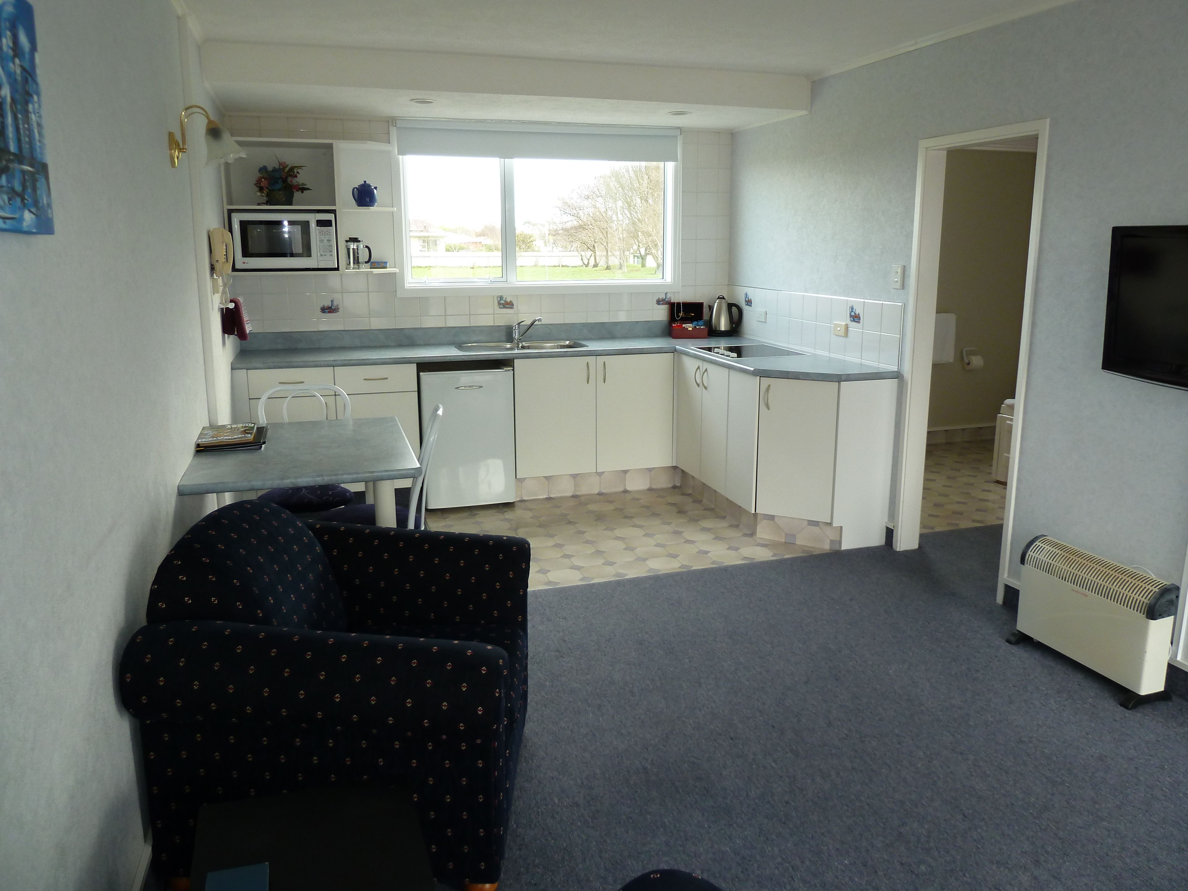 A compact kitchen with a dining area, a microwave, a sink, and a window.