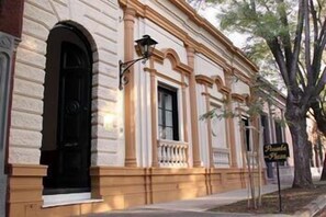 A building with a classic architectural style, featuring a prominent arched doorway and a balcony with a railing. - Posada de la Plaza (San Antonio de Areco)