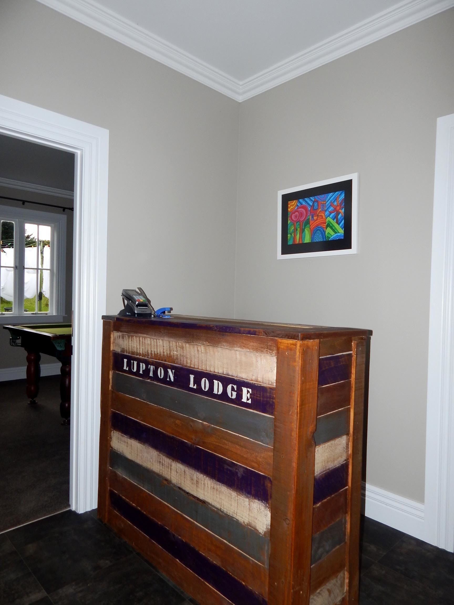 Un mostrador de recepción con la leyenda 'Lupton Lodge', con un cuadro abstracto enmarcado en la pared.
